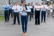 Gruppe von Büroangestellten steht im Freien auf einer Terrasse und führt gemeinsam eine Achtsamkeitsübung durch. Alle Personen stehen in einer Linie, tragen Businesskleidung und halten die Hände in Gebetshaltung vor der Brust. Gruppe von Büroangestellten steht im Freien auf einer Terrasse und führt gemeinsam eine Achtsamkeitsübung durch. Alle Personen stehen in einer Linie, tragen Businesskleidung und halten die Hände in Gebetshaltung vor der Brust.